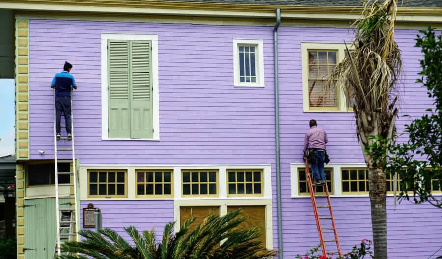 2 people painting a house purple