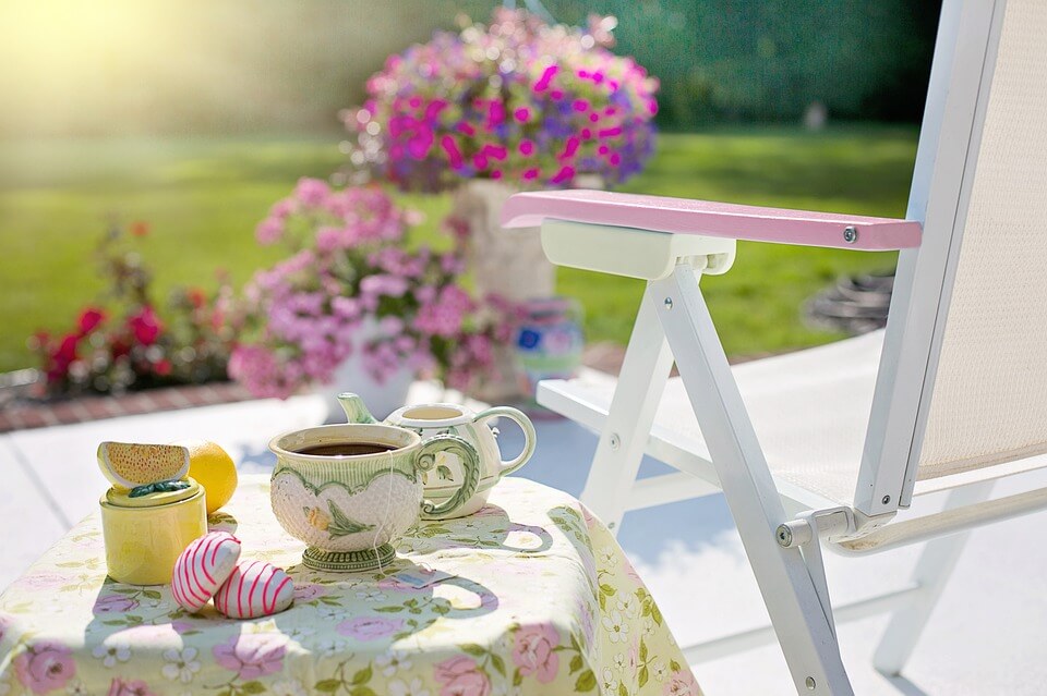 Table with tea and cookies, chair and lots of flowers