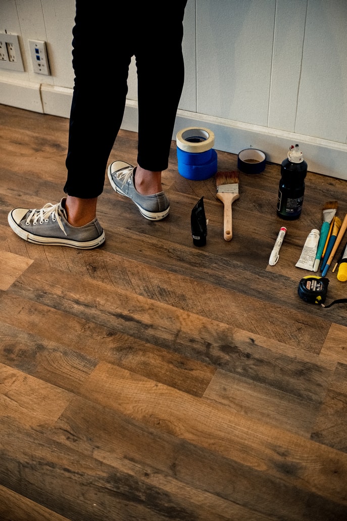 Hardwood floor with tape, paint brushes on it