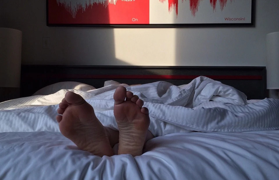 Person sleeping in a bed, feet sticking out