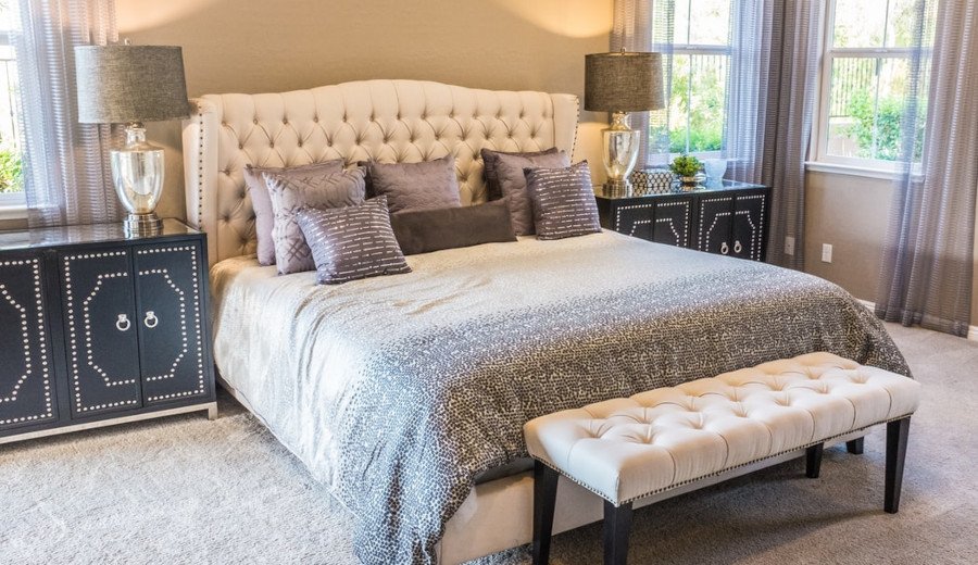 Tufted white bed near a window