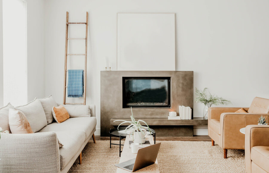 Livingroom, white sofa, fireplace, laptop and plant on a table.