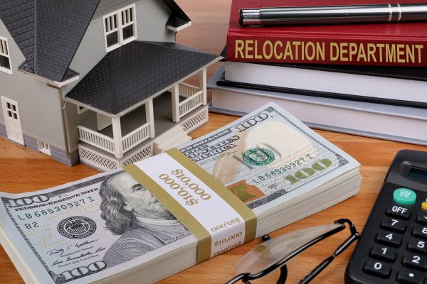 Money, glasses, books, house, calculator on a table.