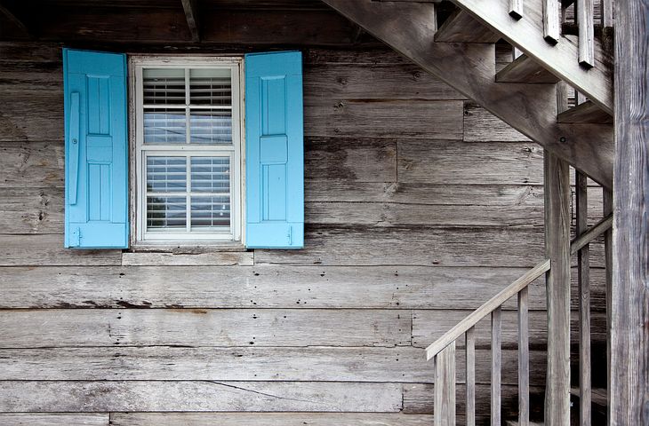 Wood house, light blue shudders around a window.