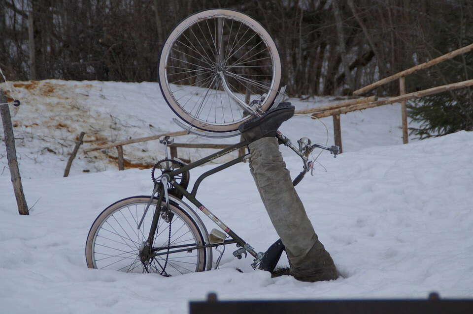 Person that has fallen off a bicycle laying in the snow.