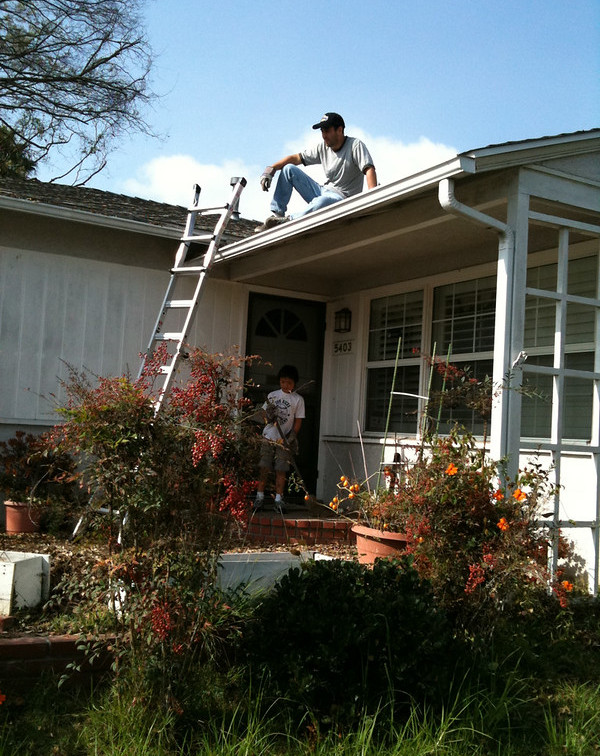House, ladder, Person sitting on top of a roof
