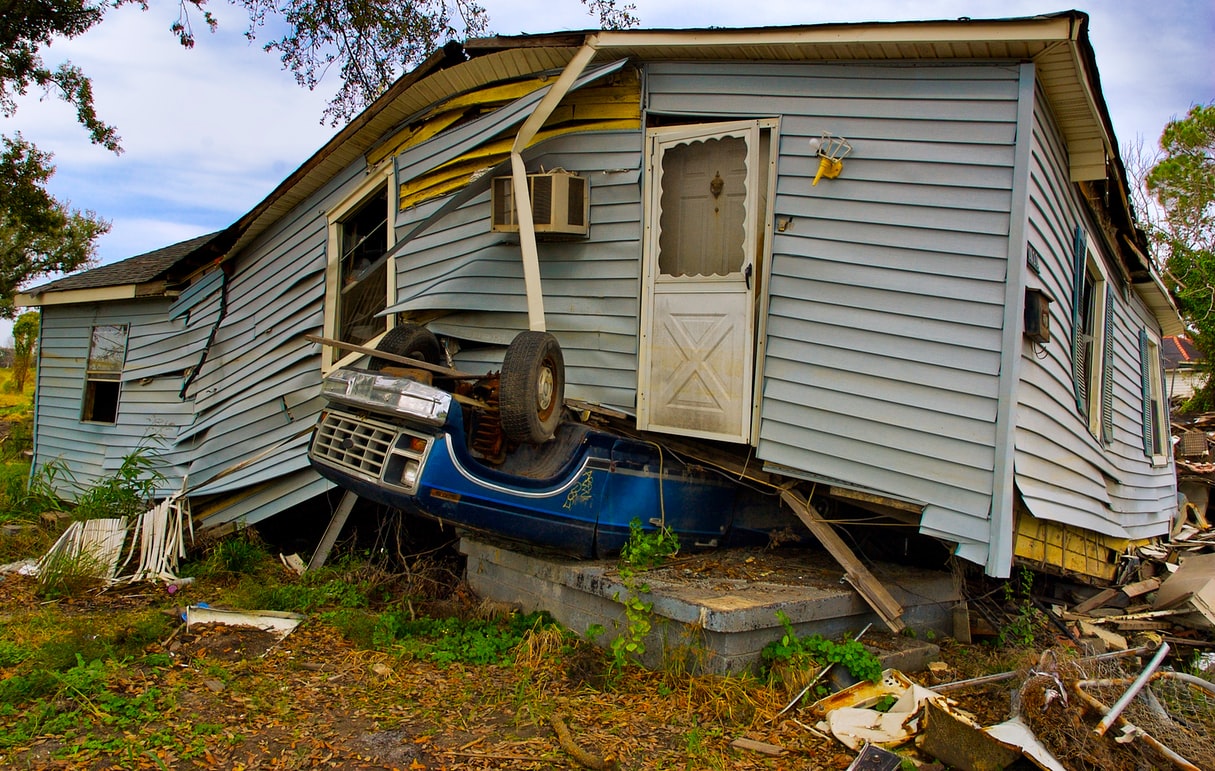 Damaged house, car under house.