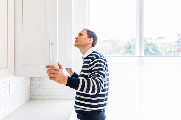 person looking inside kitchen cabinets