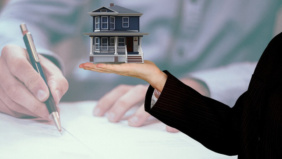 person signing a paper, person holding a house in their hand