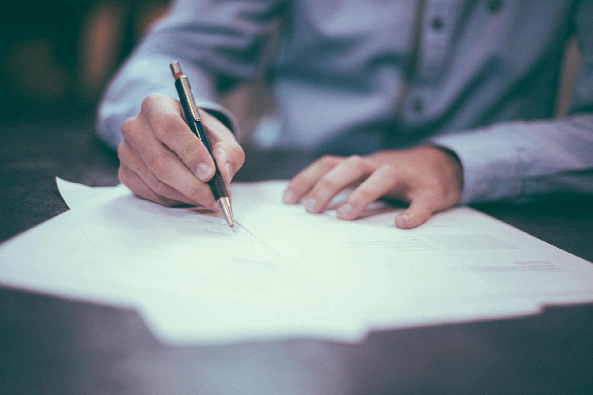 person signing paper. Image by Unsplash