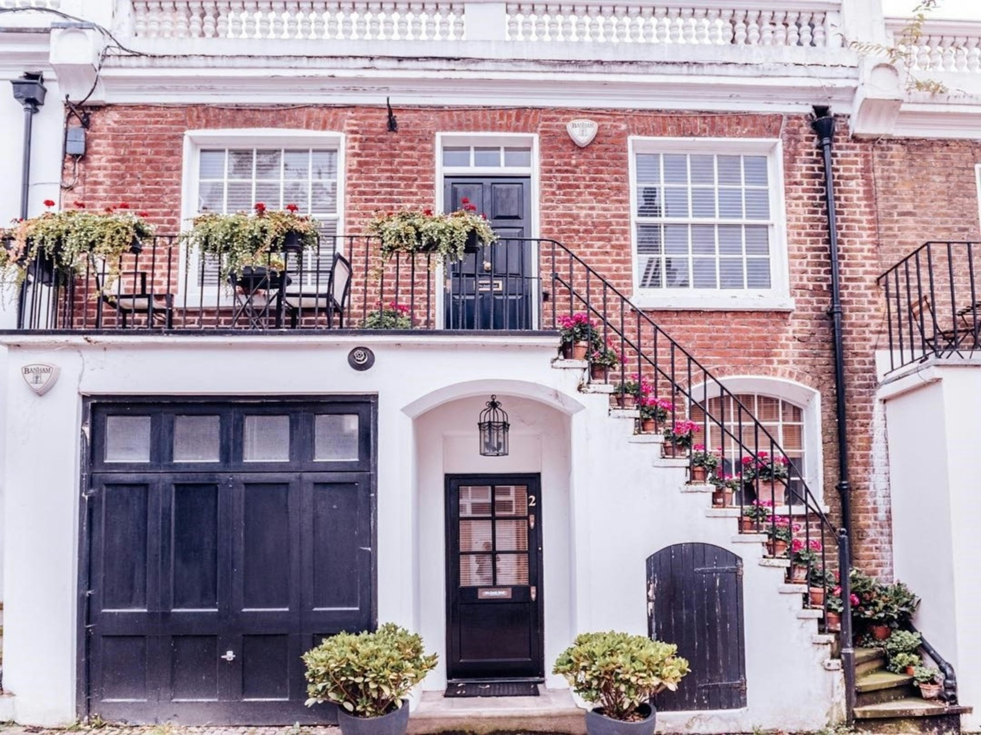 Brick house with a large staircase, one car garage. Plants on stairs. Image by Unsplash.