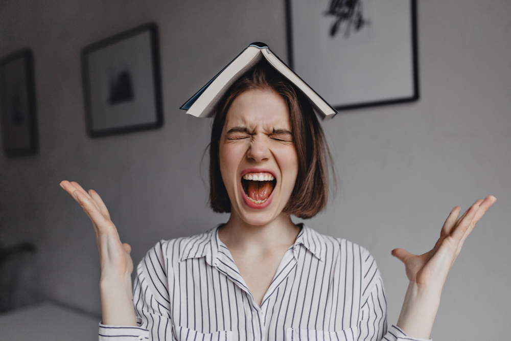 Person with a book on their heasd, screaming