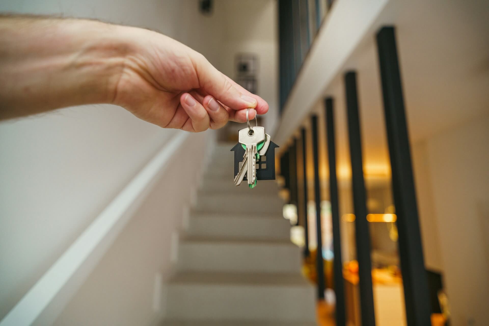 House keys being held in front of a staircase. Image via Unsplash