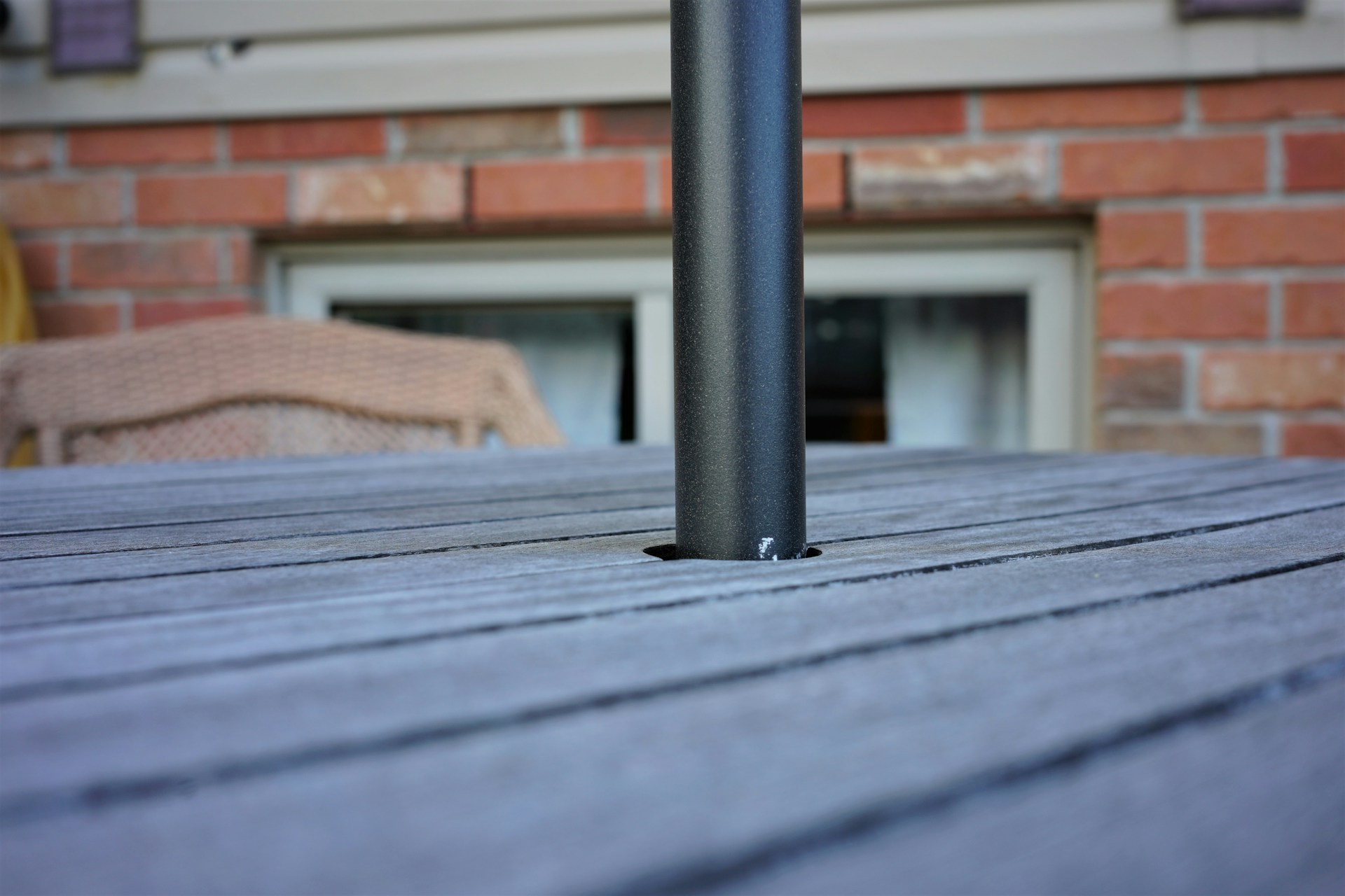 Outdoor table with an umbrella post. Image by Unslash