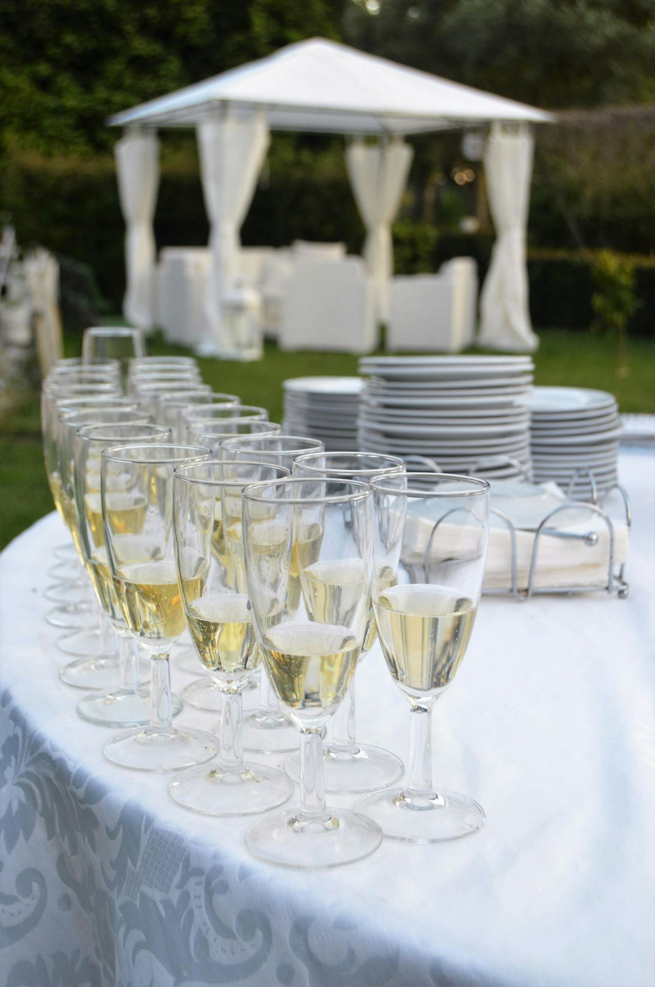 Pop up tent in the backgroud. Glasses and plates on a table. Image by Pexels