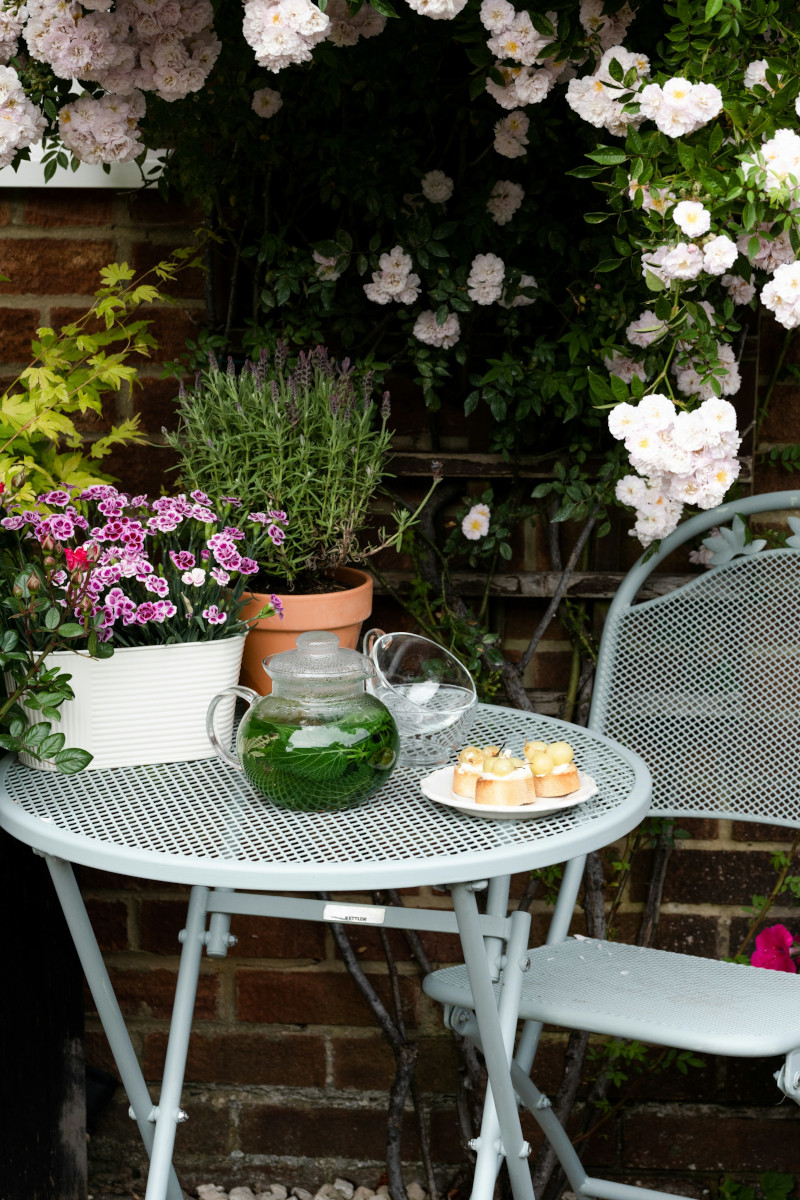 'Outdoor table and chair, flowers in the background. Image by Unsplash.