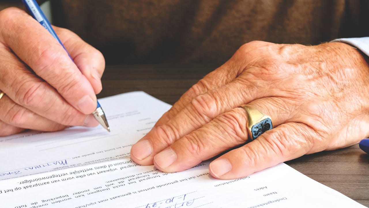 Person signing a paper. Image by Pexels