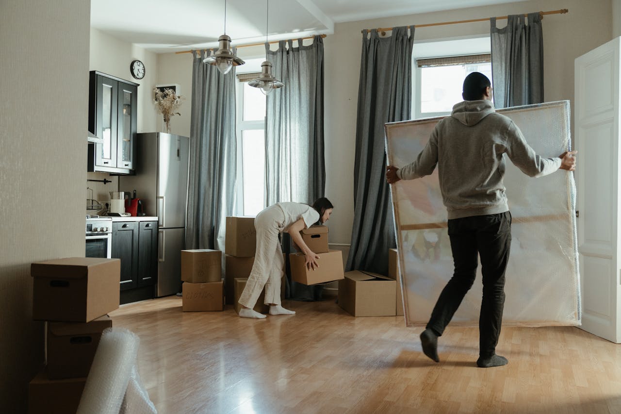 Couple unpacking moving boxes in a bright Boston apartment with large windows. Photo by cottonbro studio on Pexels