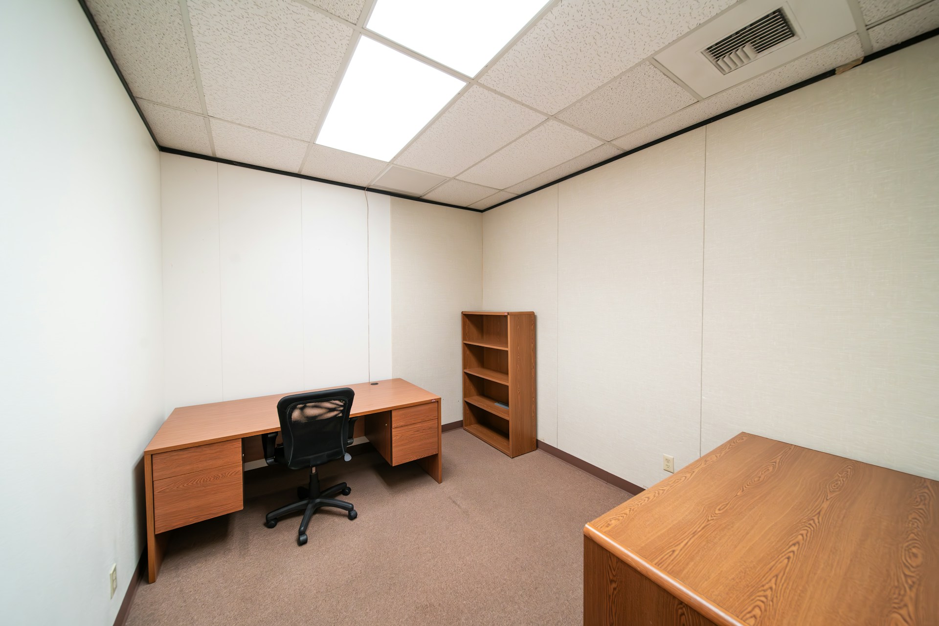 Office with empty desk and book shelves, white walls. Image by Unsplash