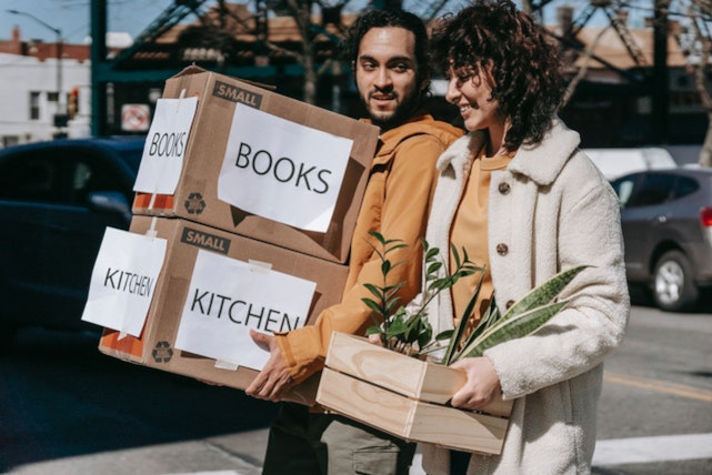 a couple carrying boxes and flowers