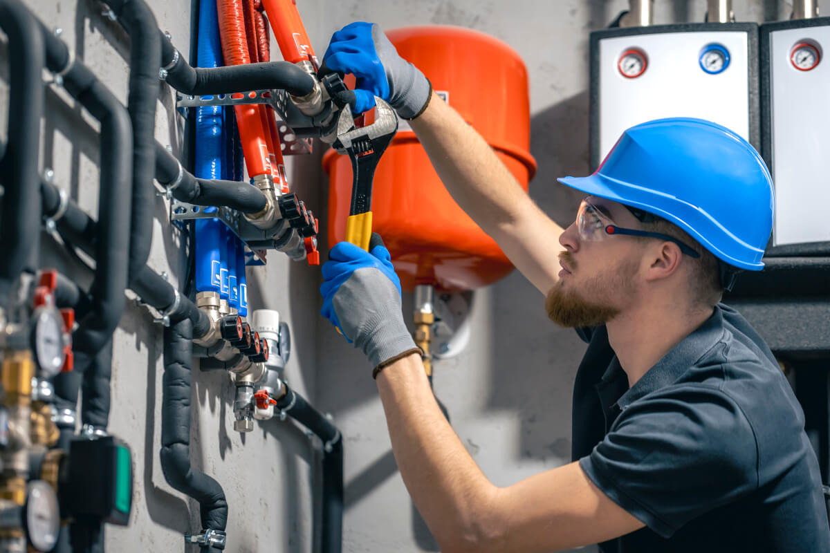 Person checking pipes with a wrench