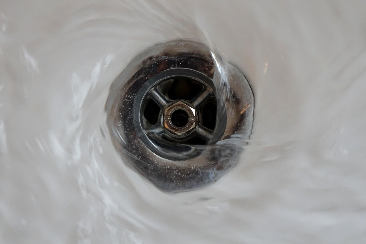 Metal sink drain with swirling water. Image by Pixabay