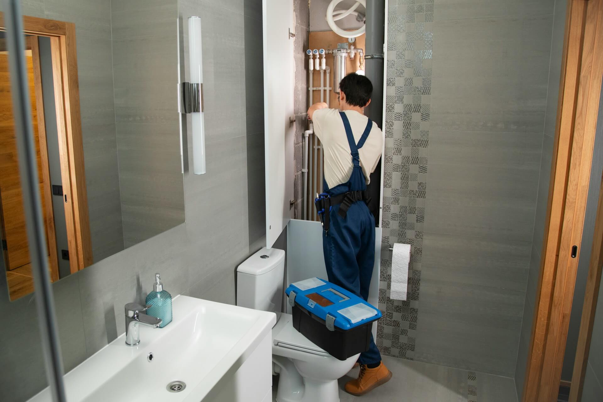 A plumber repairs plumbing in a bathroom. Image by Unsplash