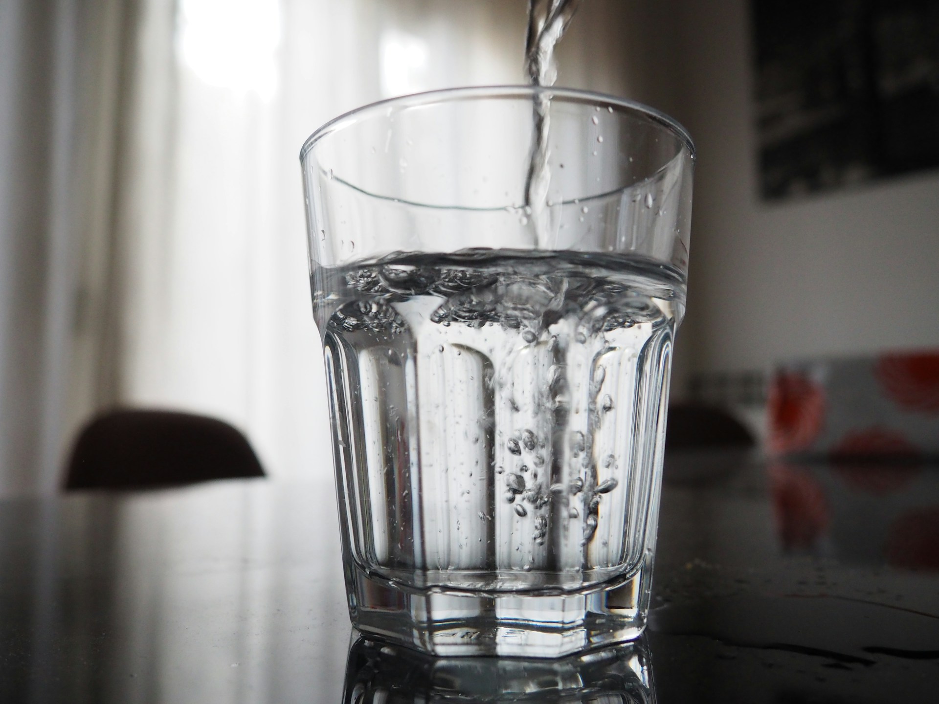 Clean water being poured from a tap into a clear glass. Image by Unsplash