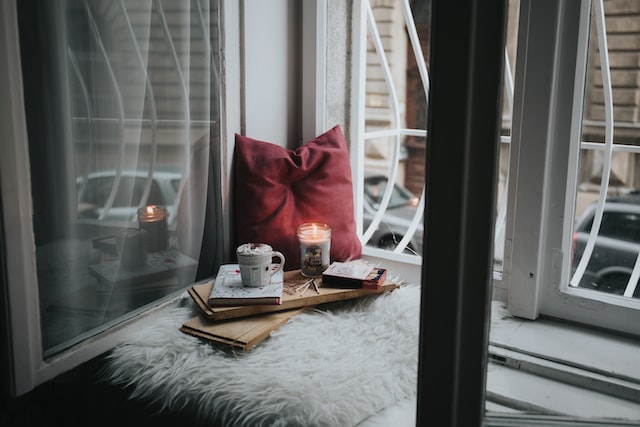 red pillow, open window, drink, candle