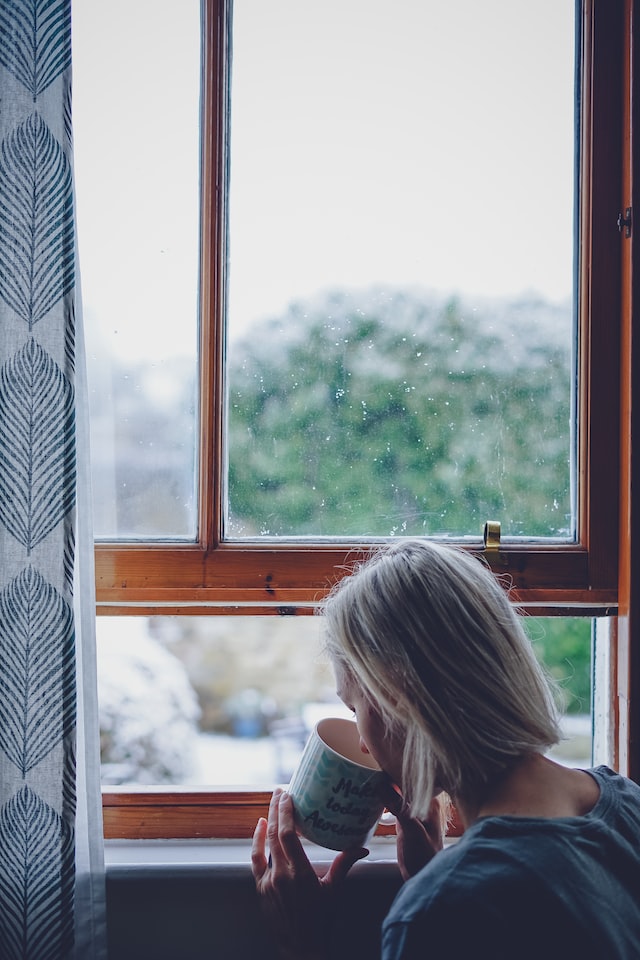 woman drinking in front of a window