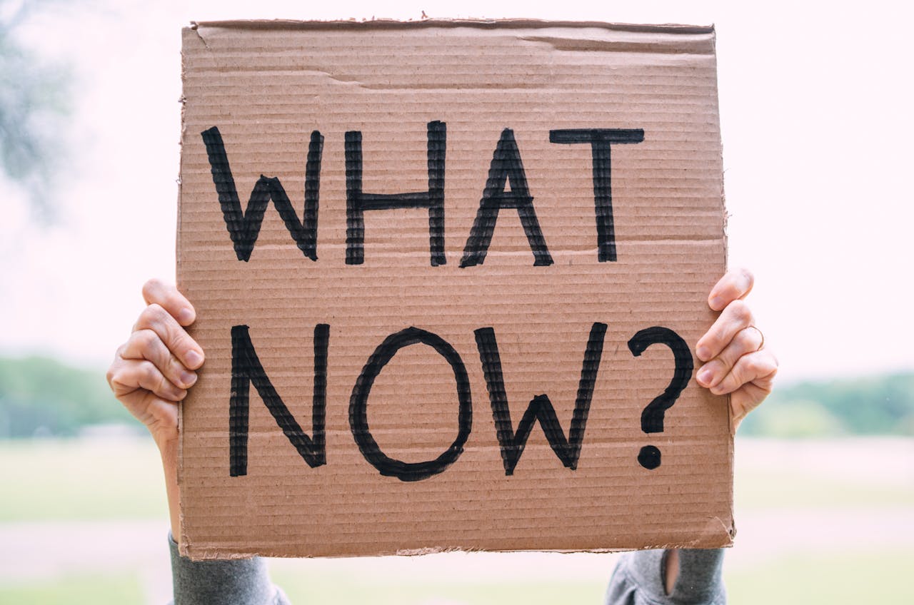 Person holding up a sign that says WHAT NOW? Image by Pexels