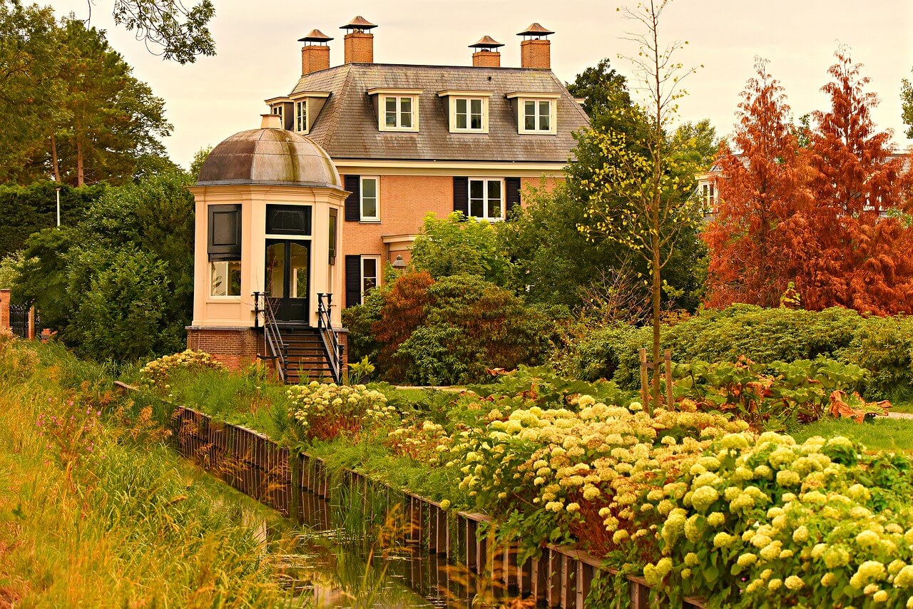 House surrounded by lots of plants, bushes and trees. Image by Pixabay