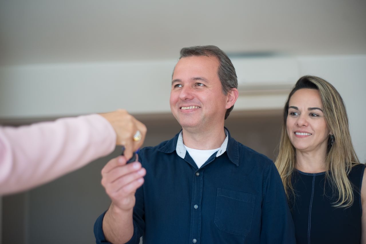 A couple receiving keys from a broker. Image by Pexels