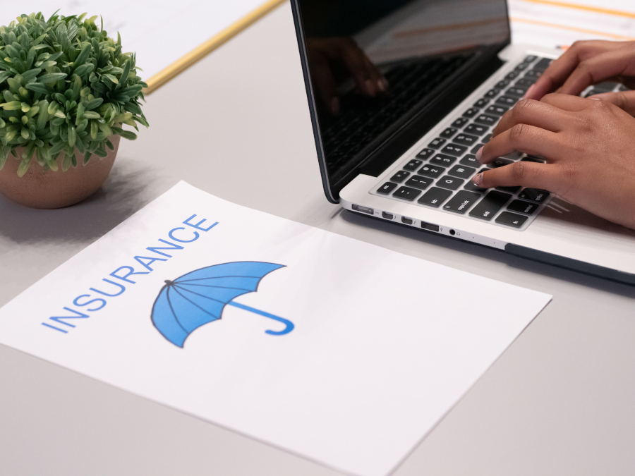 laptop, paper with umbrella and the word insurance