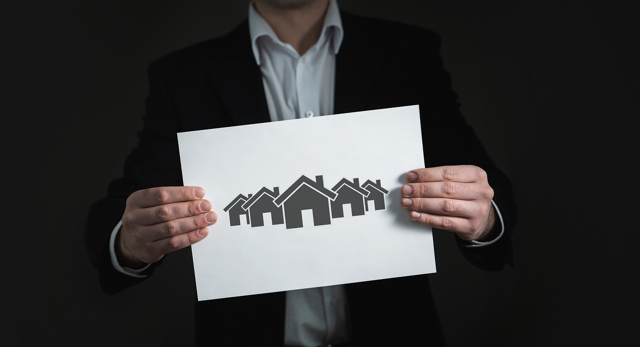 Person holding a piece of paper with houses on it. Image by Pixabay.