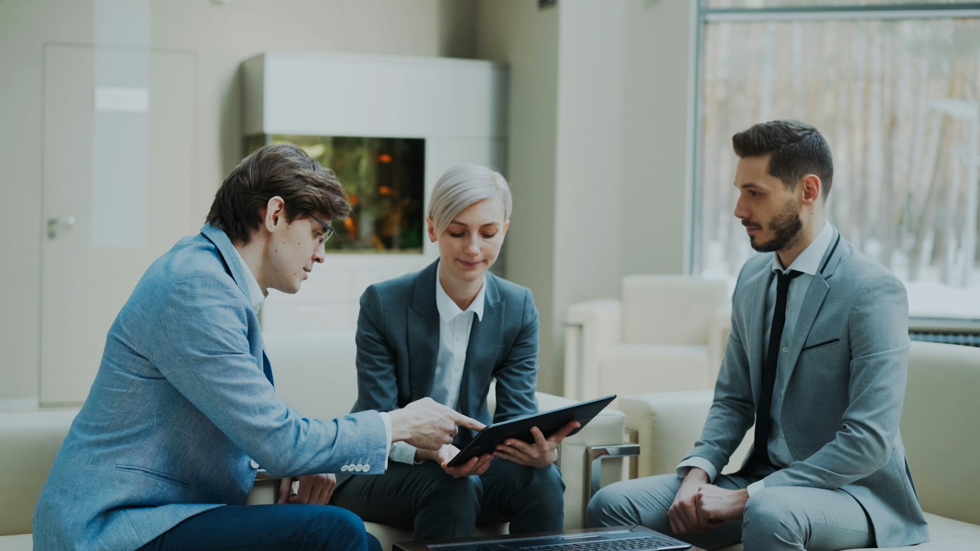 Three professionals discussing a tablet in a modern office. Image by Unsplash