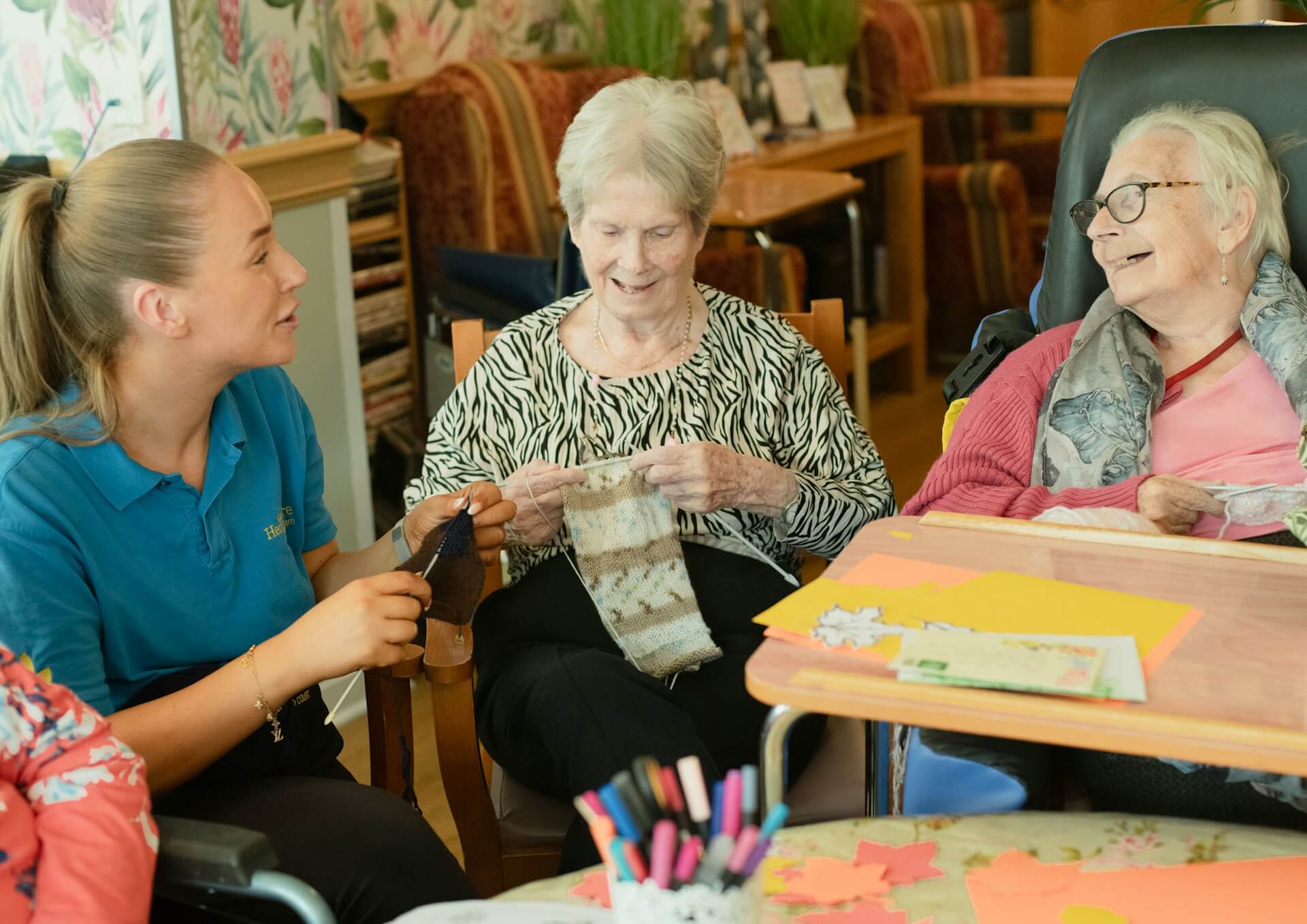 Caregiver assisting elderly people with knitting. Image by Unsplash