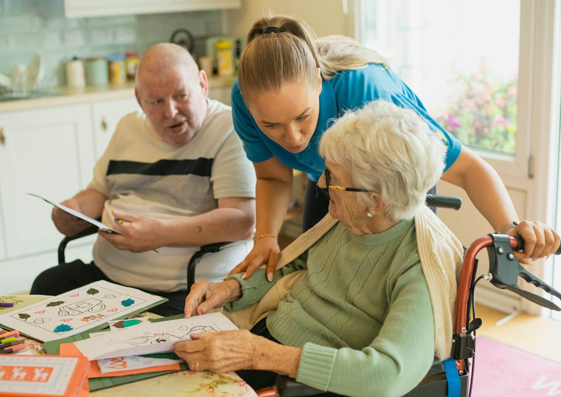 Caregiver assisting an elderly couple with coloring. Image by Unsplash