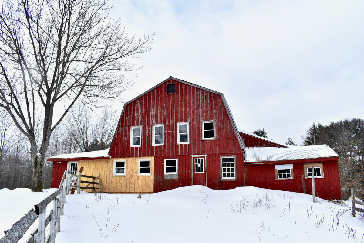 A New England house with a steep roof under light snow in winter. Photo by B.W. Ruhl on Unsplash