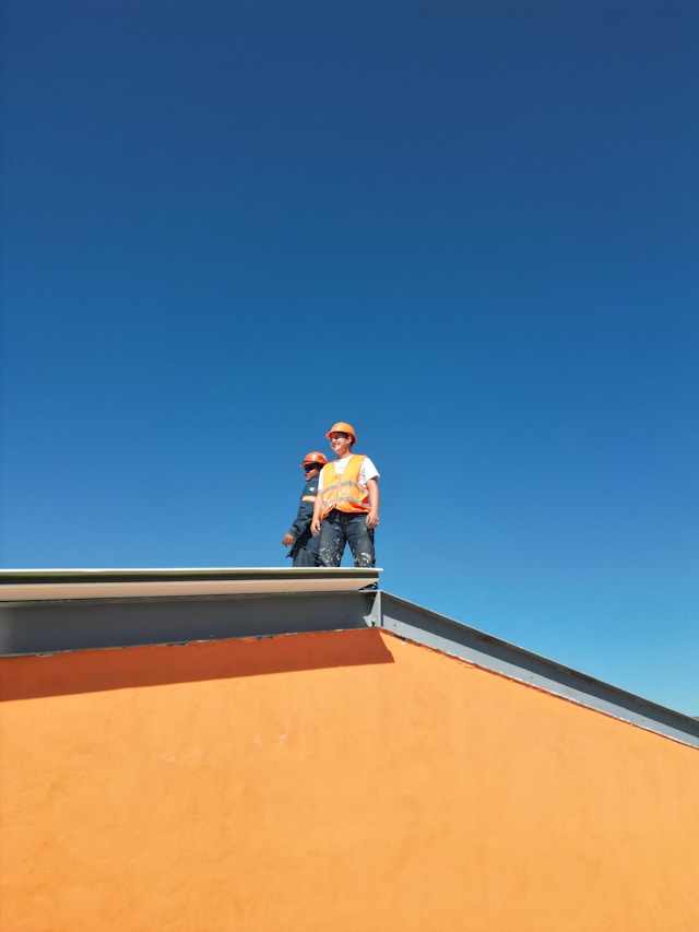 2 people on the roof of a yellow house. Image by Unsplash