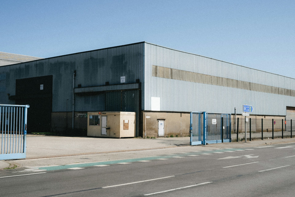 Large industrial warehouse with blue gates and road. Image by Unsplash