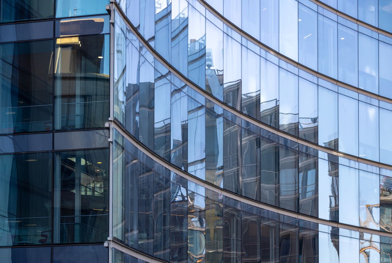 Curved glass facade reflecting an urban scene. Image by Pexels