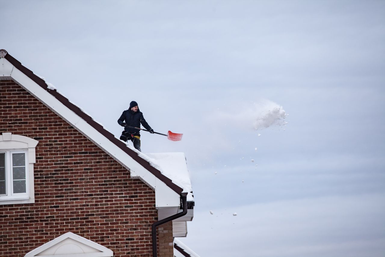 Man removing snow from a rooftop using a shovel. Image by Pexels