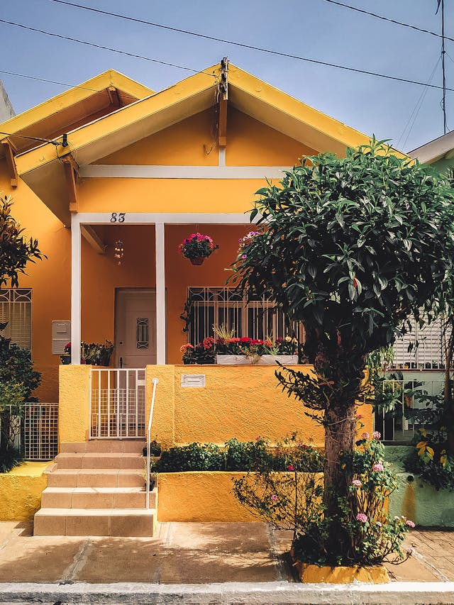 yellow house, lots of plants. Image by Pexels