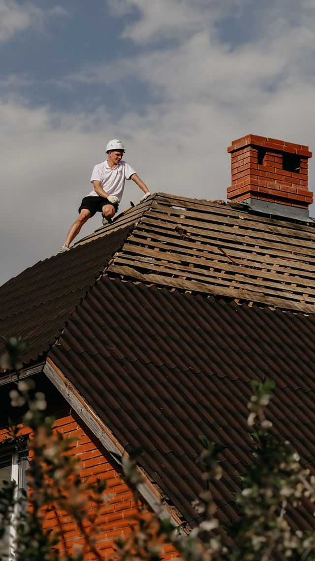 Worker on roof conducting repairs on a sunny day. Imagr by Pexels