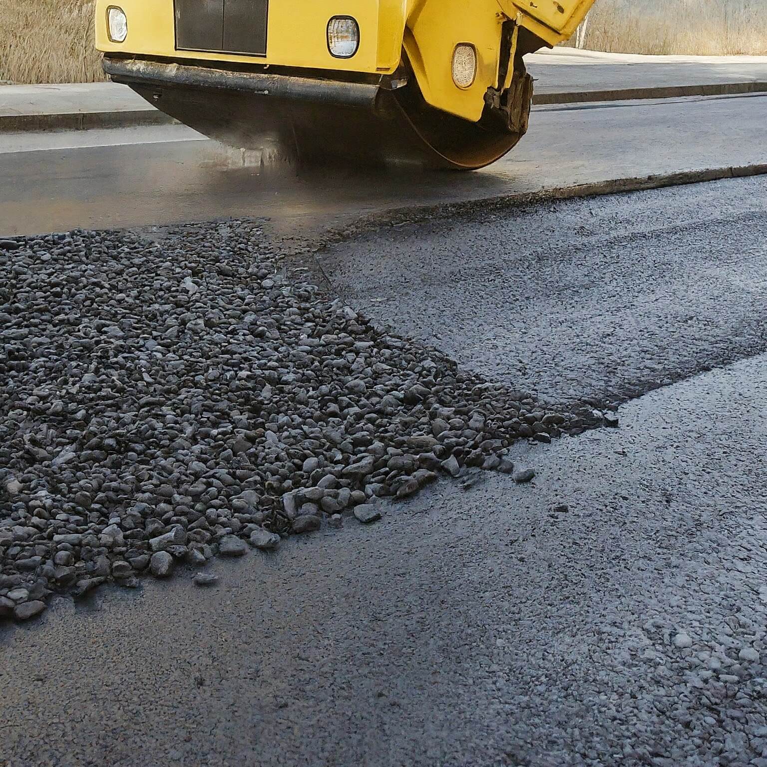 worker leveling fresh asphalt on a road construction. Image by Gemini