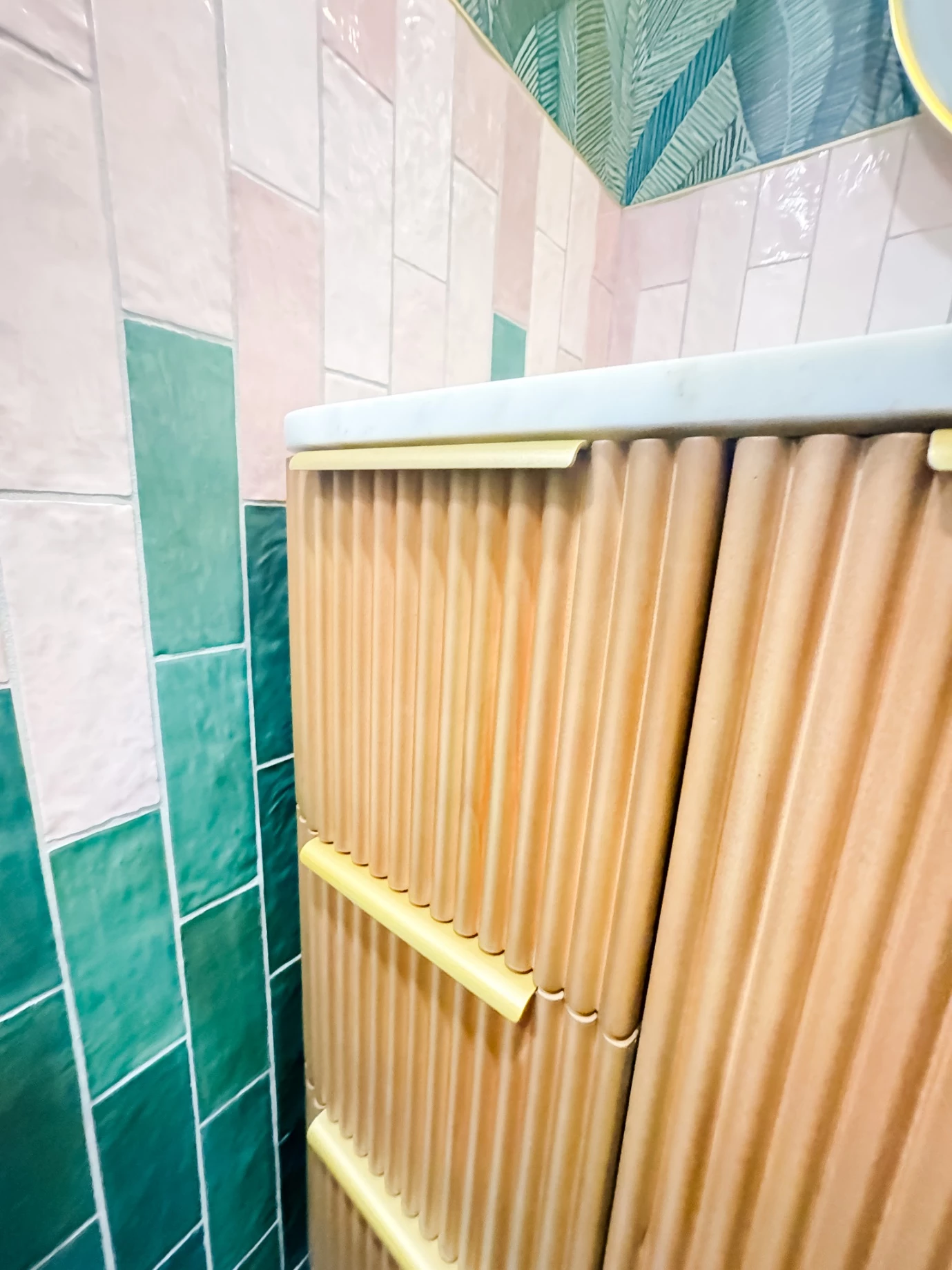 Wood cabinet with brass accent and smooth zellige tiles contrasting with cabinet doors