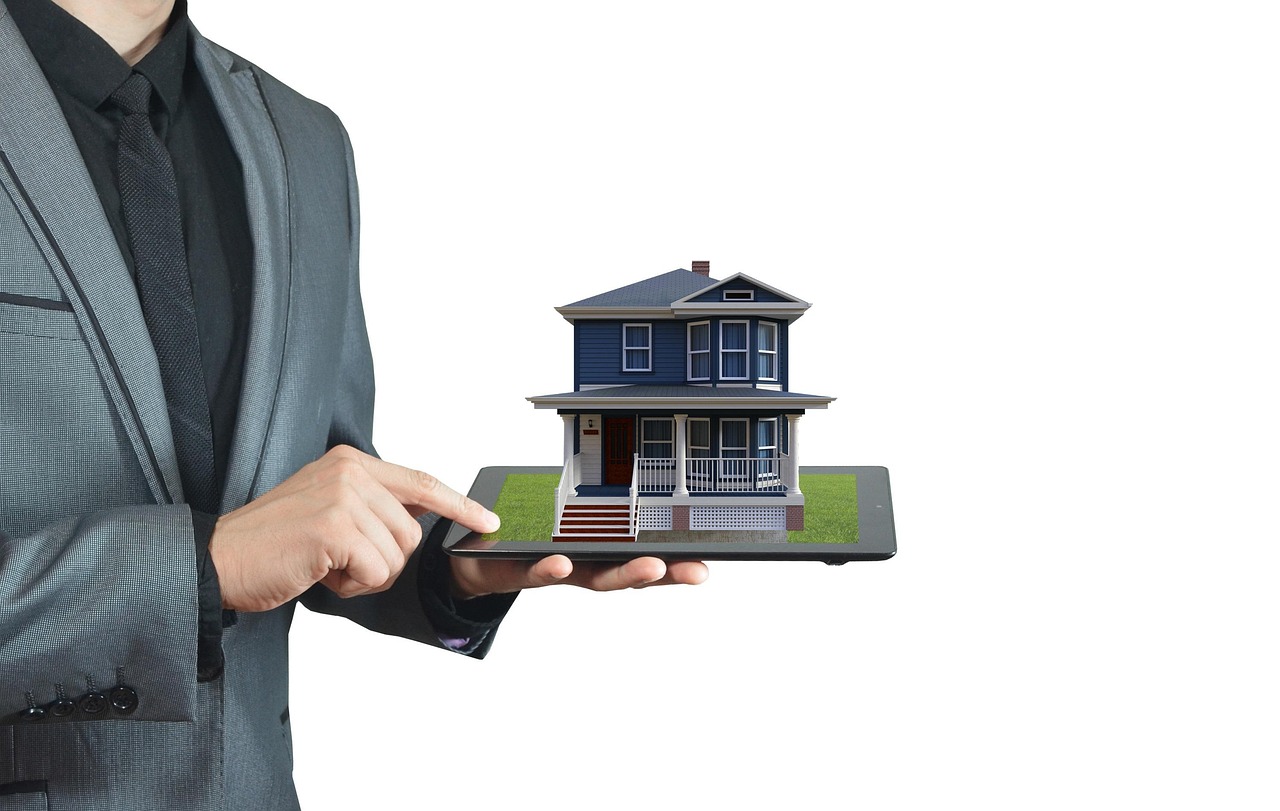 Person holding a blue house with a white porch in their hands. Image by Pixabay