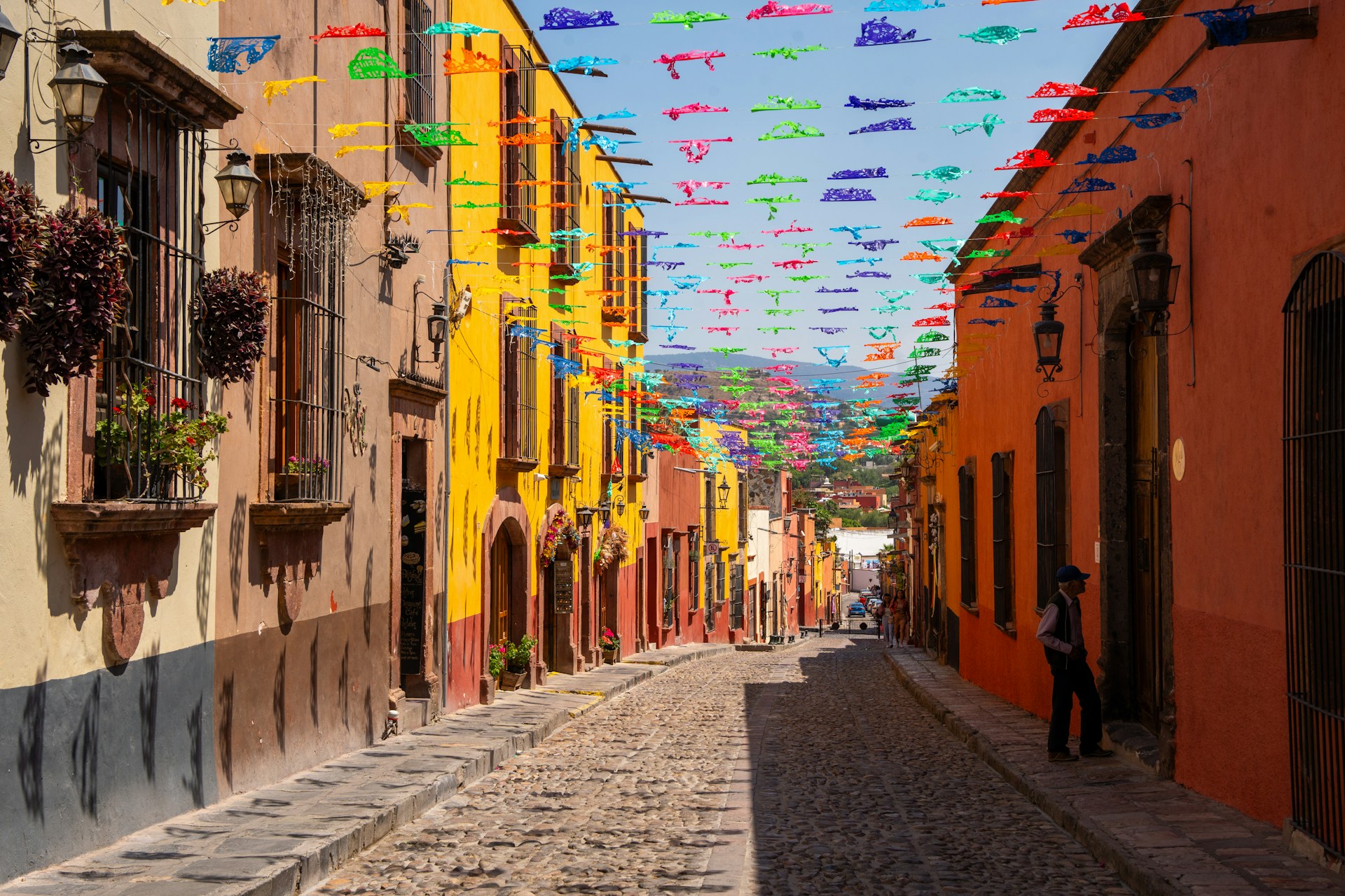 Cobblestone street lined with colorful flags. Image by Unsplash