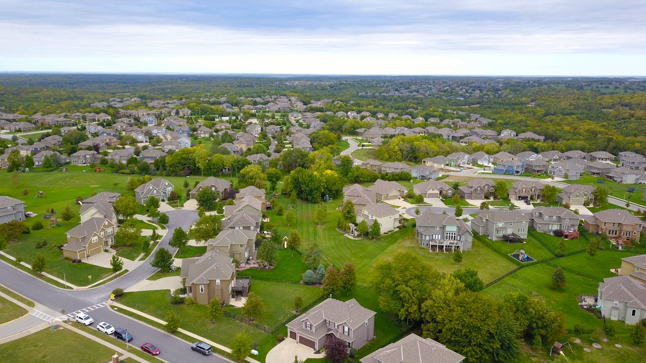 Arial view of houses, lots of green lawns. Image by Pexels